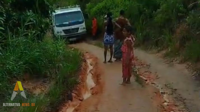 Estrada rural com lama e buracos na região de Ibirataia, com caminhão atolado e dificuldade de acesso